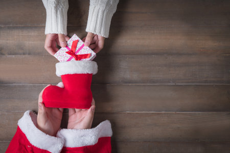 child hand sent gift into Santa Claus shoes on Christmas Day. Old wood  background with copy space.の写真素材