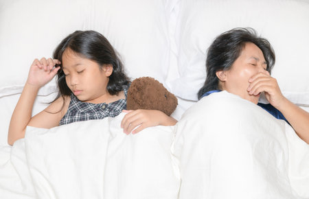 Mother yawn and  slepp with her daughter on bed, relax and tired concept.の写真素材