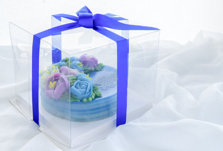 Minimal cake decorated with cute flowers in a plastic box on white cloth.の写真素材