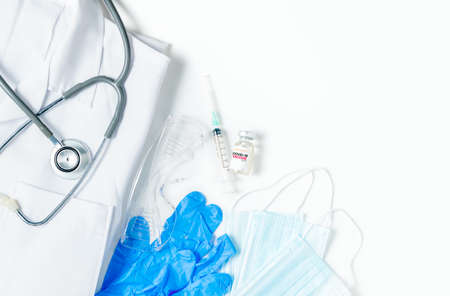 A vial of the vaccine with syringe and stethoscope on gown shirt isolated on white background