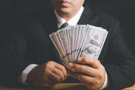 Businessman hand holding money - United States Dollars. investment, success and profitable business conceptsの写真素材