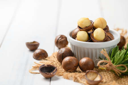 Dry Roasted Macadamia Nut in white cup on white wood background,Macadamia nuts are loaded with...