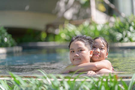 Happy brother and sister are playing in swimming pool, rest and recreation on summerの写真素材
