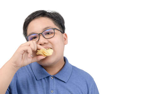 Obese fat boy eating potato chips isolated on white background, unhealthy food or junk food conceptの写真素材