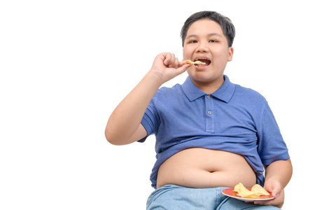 Obese fat boy eating potato chips isolated on white background, unhealthy food or junk food conceptの写真素材