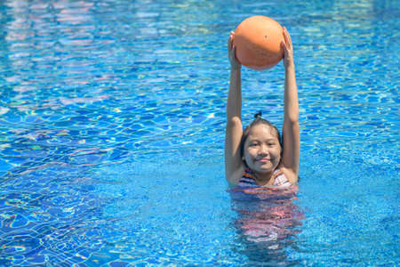 Happy girl playing ball in swimming pool, recreation and leisure in holiday conceptの写真素材