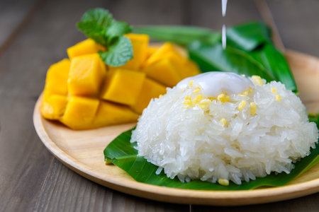 motion of coconut milk on Coconut Flavored Sticky Rice with Ripe Mango on wood dish, 
Popular Thai desserts on summer.の写真素材