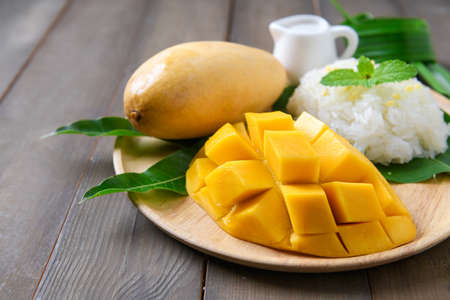 Ripe Mango with Coconut Flavored Sticky Rice on wood dish, 
Popular Thai desserts on summer.の写真素材