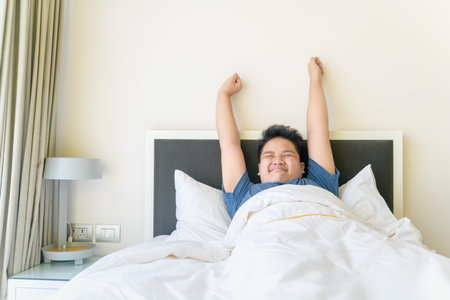 obese fat boy wakes up and stretching on bed in morning, Health care and good morning world concept