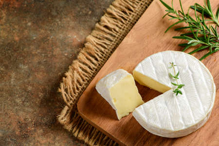 Camembert Cheese with thyme on wood plate. Camembert is a moist, soft, creamy, surface-ripened cow's milk cheese.の写真素材
