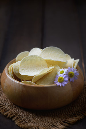 Potato chips bowl on  wood background, fat food or junk food concept