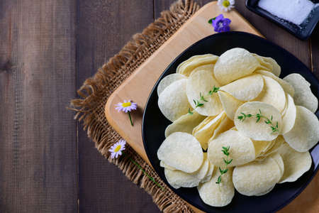Top view of Potato chips bowl and salt on wood background with copy space, fat food or junk food...