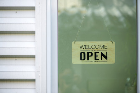 Reopening of a small business activity after the covid-19 emergency, ended the lockdown and quarantine. A wood business sign that says now we are open hang on door at entrance.の写真素材