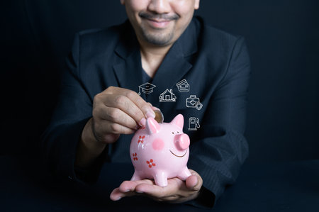 businessman putting money coin into piggy for saving money with expenses icons on black background, save money planning conceptの写真素材