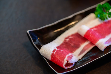 Sliced wagyu marbled beef for yakiniku on plate on black background, Premium Japanese meat conceptの写真素材