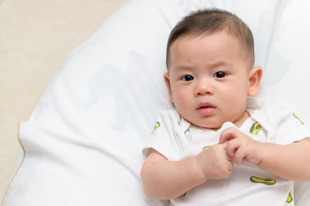 happy baby boy lying on white bed and look at camera. health care infant conceptの写真素材