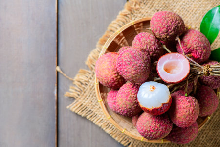 tyop view of Juicy Fresh Lychee in Bamboo Basket on Rustic Wooden Table â€“ Tropical Exotic...