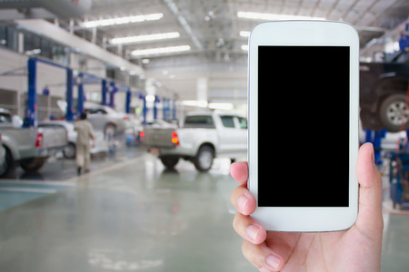 hand hold smartphone with car repair service center backgroundの写真素材