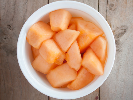 closeup melon slice in white dish with wood table backgroundの写真素材