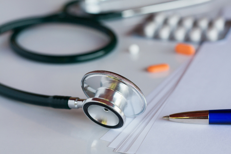 Stethoscope with pen and medicine pills on white backgroundの写真素材