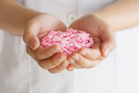 many pink medicine pills in doctor handsの写真素材