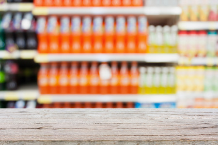 wood table over soft drink bottles on shelves in supermarket blur backgroundの写真素材