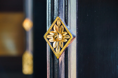 Thai style art golden flower carving on the windowの写真素材