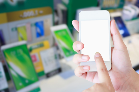 Female hand holding mobile smart phone over phone store blur background, mobile smartphone shop conceptの写真素材