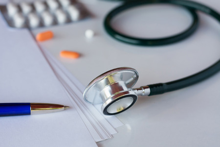 Stethoscope with pen and medicine pills on white backgroundの写真素材