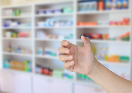 pharmacist hand holding something with blur some shelves of drug in the pharmacy drugstoreの写真素材