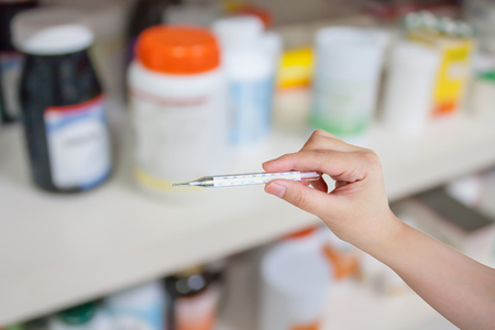 Doctor holding a medical thermometer in medical office
