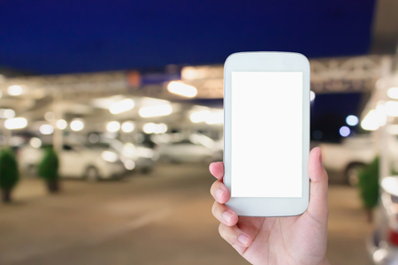 hand hold and touch screen smart phone on abstract car parking at nightの写真素材