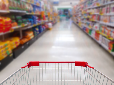 supermarket shelves aisle blurred background with shopping cartの写真素材