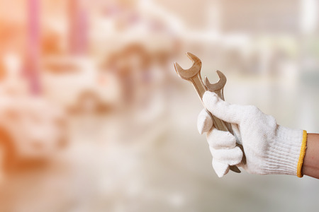 Mechanic holding pair of wrench at car servicing centreの写真素材