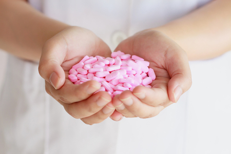 many pink medicine pills in doctor handsの写真素材