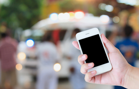 hand hold smartphone with Ambulance responding to an emergency call backgroundの写真素材