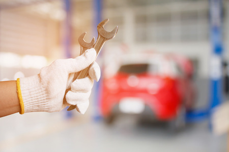 Car mechanic holding wrench at the car repair service garageの写真素材