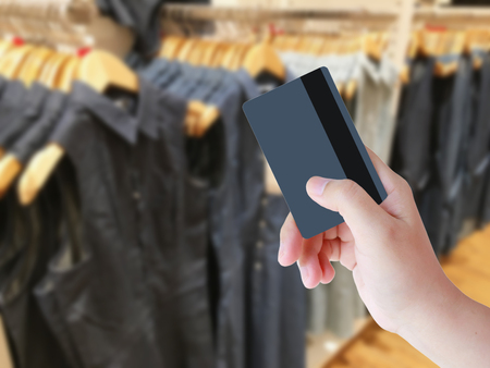 hand holding credit card with clothing store blurred backgroundの写真素材