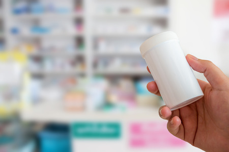 closeup hand of female pharmacist with medicine bottle at the pharmacyの写真素材
