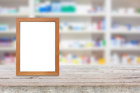 wood photo frame on the pharmacy counter over blur shelves of drug in the pharmacy drugstore backgroundの写真素材