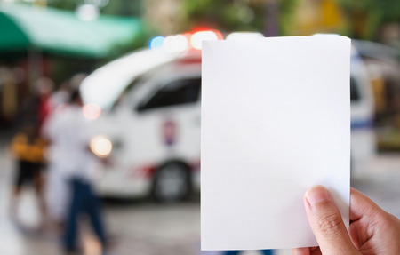 hand hold white paper with Ambulance responding to emergency call backgroundの写真素材