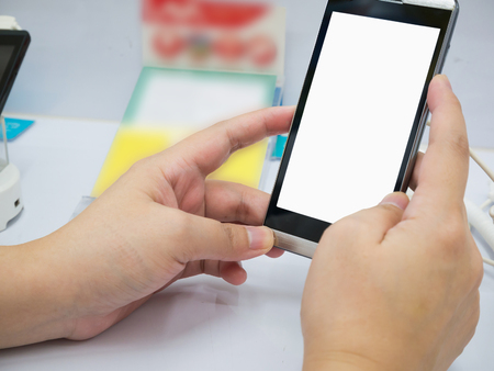 female hand hold mobile smartphone in mobile phone shop with mobile phone store blur backgroundの写真素材
