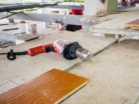 Close up electric drill at work site on wooden boardの写真素材
