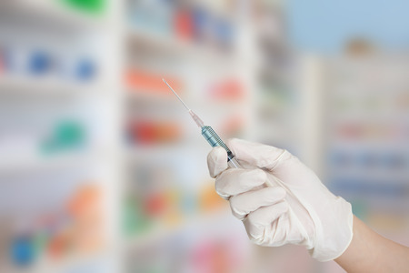 doctors hand with syringe with blur drug shelvesの写真素材