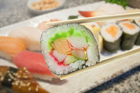 Sushi maki in chopsticks with Japanese sushi setの写真素材
