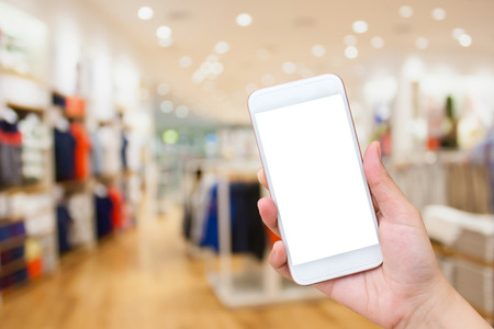 Close up of woman using Cell phone in clothing storeの写真素材
