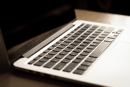 open laptop with black screen on modern wooden desk, angled notebook on table in home interior with vintage filterの写真素材