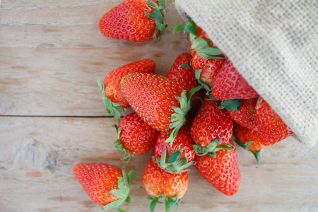 strawberries in small sack on wooden table backgroundの写真素材