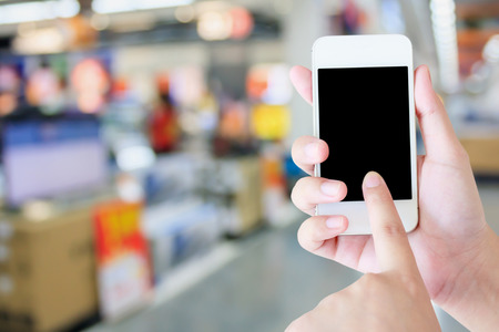hand hold mobile phone with eletronic department store with bokeh blurred backgroundの写真素材