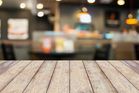 Empty wood table with cafe restaurant blur background with bokehの写真素材